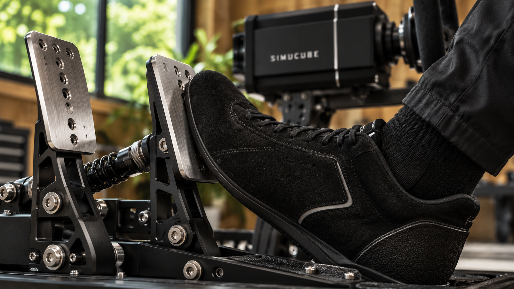 Driver applying a load cell brake on a rigid sim racing pedal platform.