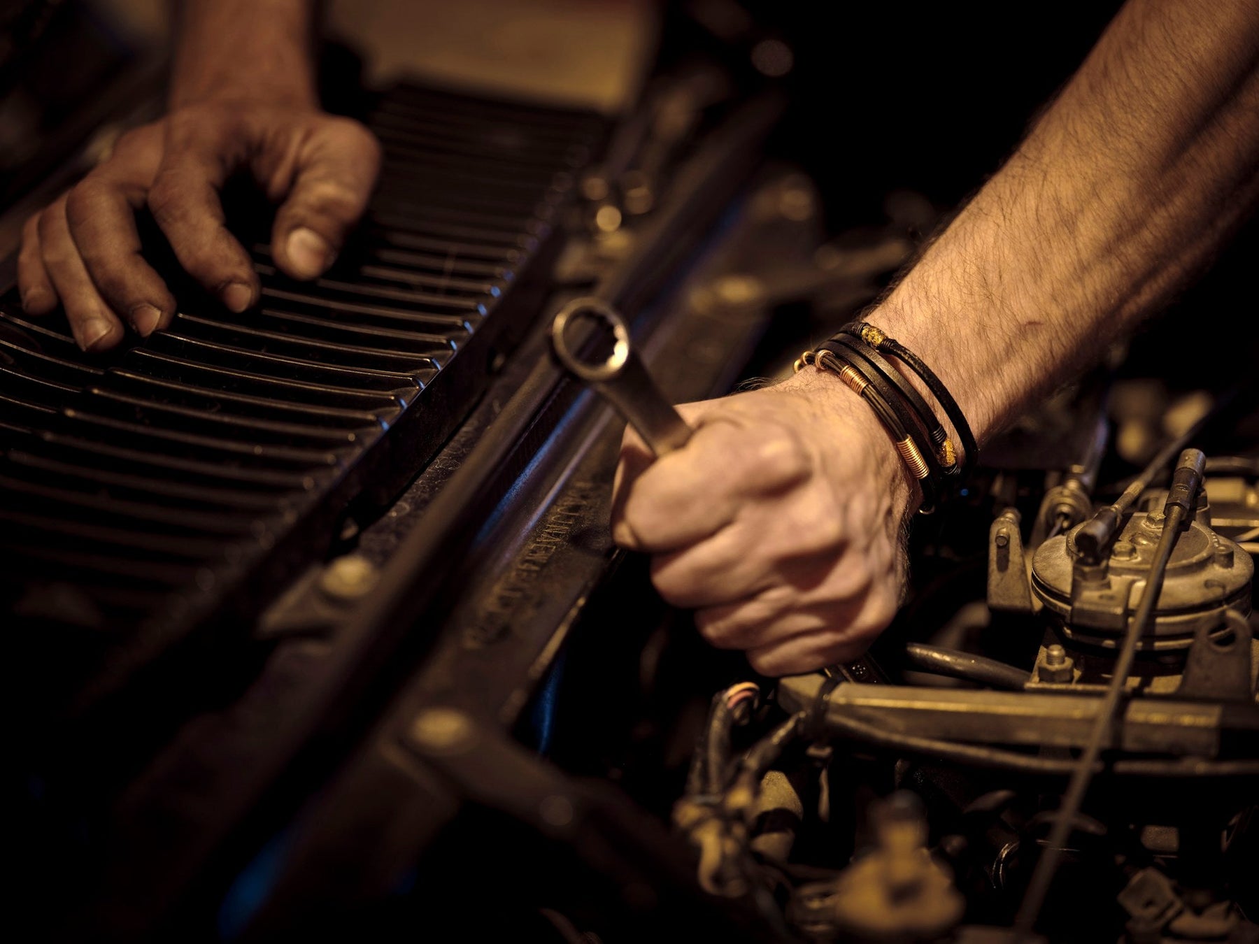 Mechanic hands tightening a bolt with a wrench in a dark garage