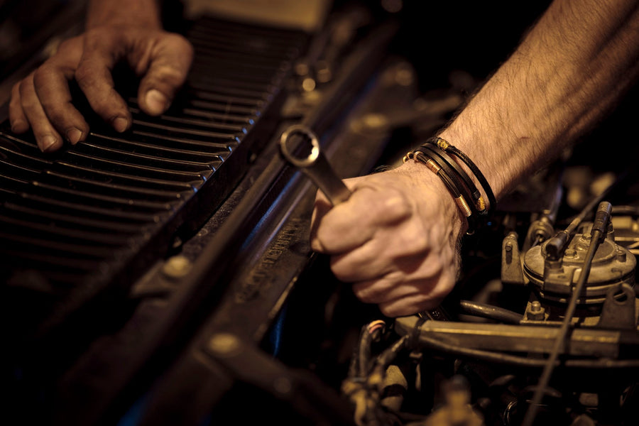 Mechanic hands tightening a bolt with a wrench in a dark garage